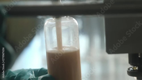 Laboratory assistants filling up bottle with body care lotion or shampoo in factory