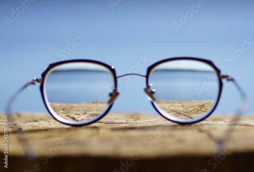 Round women`s glasses with a black frame lie on a stump