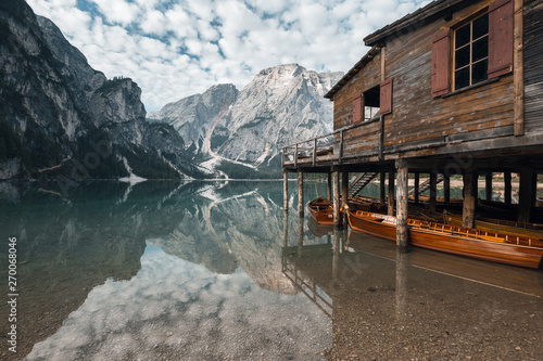 House on the Water, fleecy clouds and mountain scenery reflect in lago di braies, italy