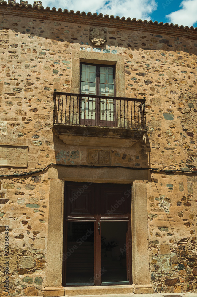 Building stone facade with door entrance and balcony at Caceres