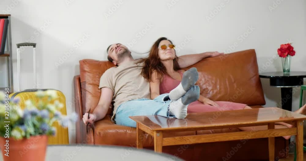 Young caucasian couple sits on couch and waits for taxi to go to airport Young caucasian couple sits on couch and waits for taxi to go to airport