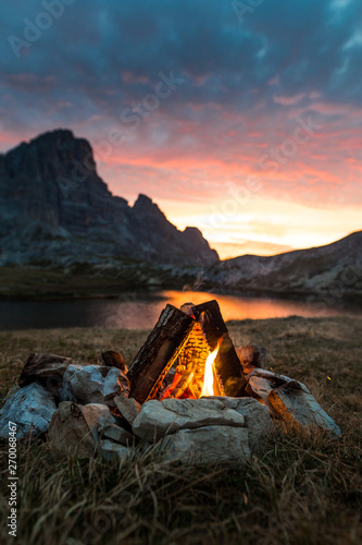 Campfire romantic near a Mountain lake with sunset sky , italy