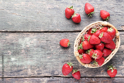 Fresh strawberries in basket on grey wooden table
