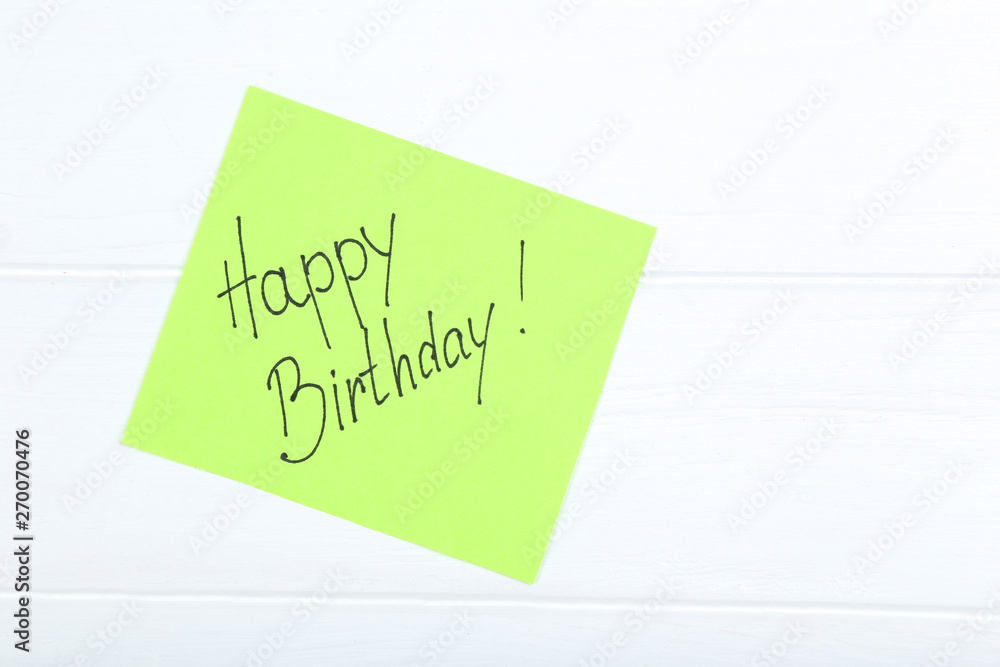 Paper with text Happy Birthday on white wooden table Paper with text Happy Birthday on white wooden table