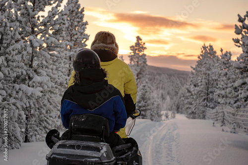 Photography 2 people riding on a snowmobile through the wilds of Lapland