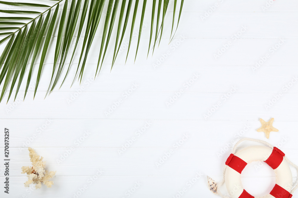 Seashells with lifebuoy and palm leaf on whtie wooden table Seashells with lifebuoy and palm leaf on whtie wooden table