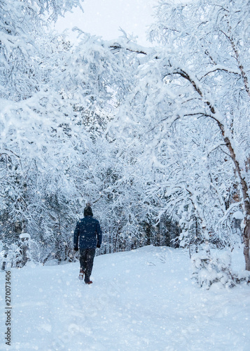 Man walking along forest track in snowy weather