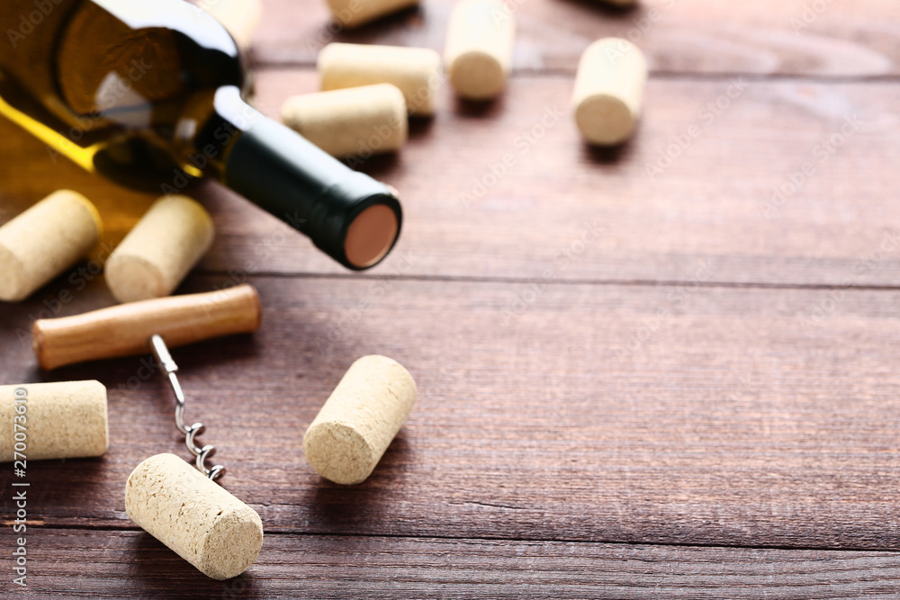 Wine bottle with corks and corkscrew on brown wooden table Wine bottle with corks and corkscrew on brown wooden table