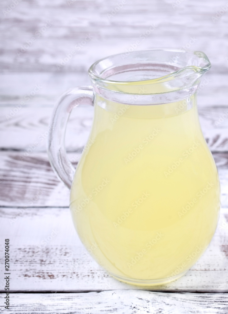 Milk whey in a glass jug against the white wooden background Milk whey in a glass jug against the white wooden background