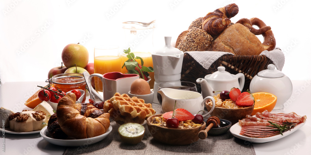 Naklejka premium Huge healthy breakfast on table with coffee, orange juice, fruits, waffles and croissants. Good morning concept.