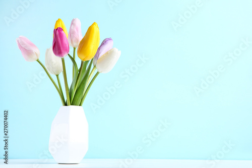 Bouquet of tulip flowers in vase on blue background