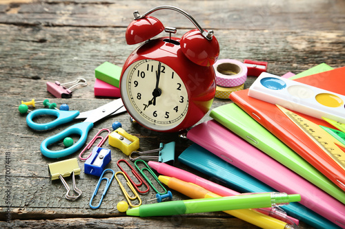 School supplies with alarm clock on grey wooden table