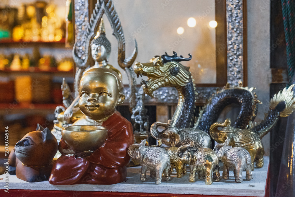Various Thai Buddha statuettes, silver elephants and dragons and other souvenirs for sale in local Bang Niang Night Market, Khao Lak, Thailand.