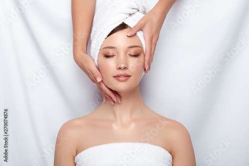 beauty master holding woman's face that lying down on white