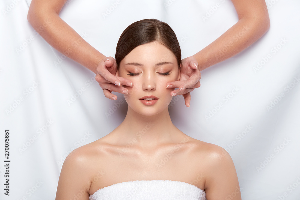 beautician massaging woman's cheeks on white, lovely girl having facial treatment, beautiful face receiving skin theraphy beautician massaging woman's cheeks on white, lovely girl having facial treatment, beautiful face receiving skin theraphy