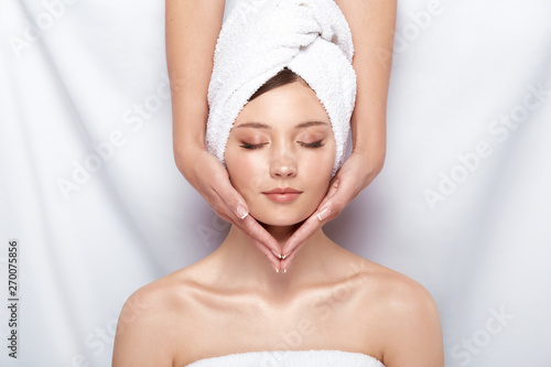 pretty woman in bath towel on her head receiving facial massage, beauty theraphy after bath, spa treatment for females