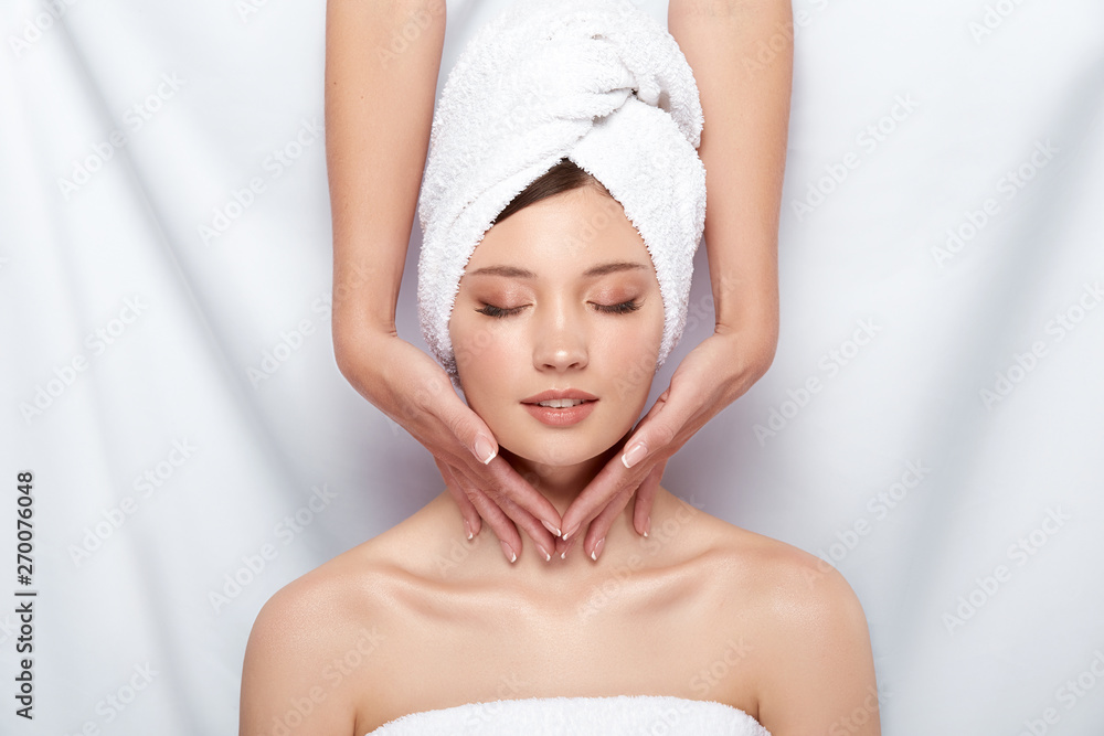 beautician massaging neck of woman in bath towel and with naked shoulders, facial procedures in spa for pretty girl beautician massaging neck of woman in bath towel and with naked shoulders, facial procedures in spa for pretty girl