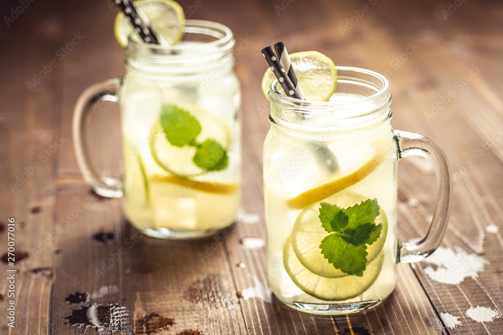 Cold Fresh Mojito Cocktail Lemonade with Ice, Lemon and Mint Leaves in Mason Jar on Rustic Dark Wooden Background. Summer Concept. Cold Fresh Mojito Cocktail Lemonade with Ice, Lemon and Mint Leaves in Mason Jar on Rustic Dark Wooden Background. Summer Concept.