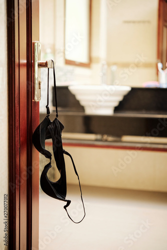 Image of black bra hanging on door handle of the open bathroom door photo