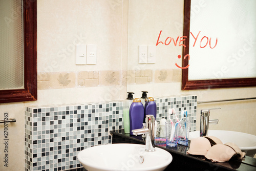 Fototapeta Naklejka Na Ścianę i Meble -  Love message written with red lipstick on the mirror in the modern bathroom