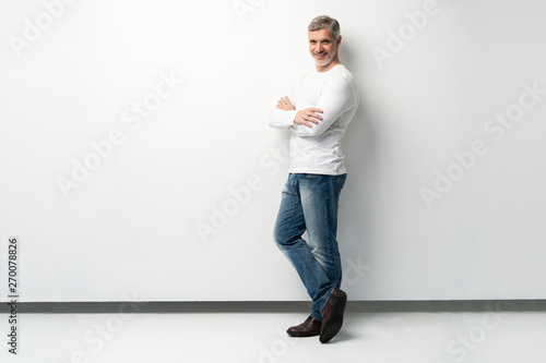 Full body portrait of relaxed mature man standing with arms crossed over white background. photo