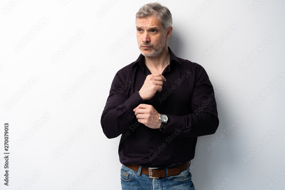 Fototapeta premium Cheerful man of middle age against white background, wearing jeans and black shirt, mid shot.