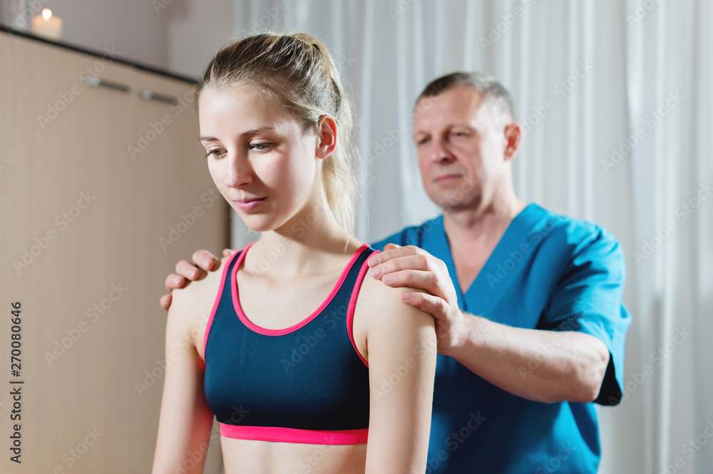 Male manual visceral therapist masseur treats a young female patient. Diagnosis of the shoulders and forearms