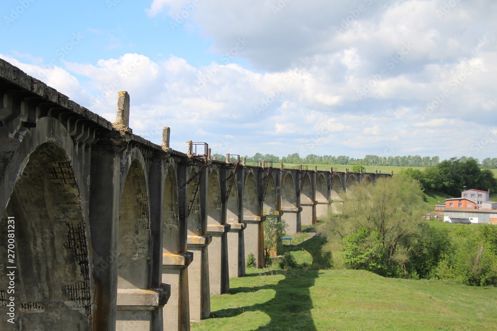 View of an old abandoned viaduct under a blue sky with white clouds