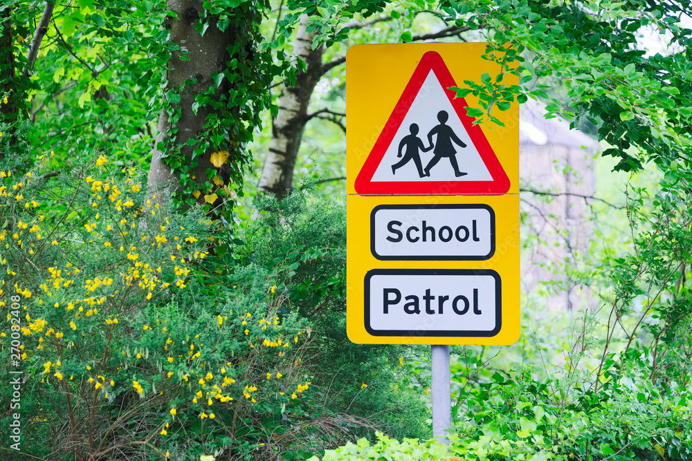 School patrol yellow and red triangle sign near entrance