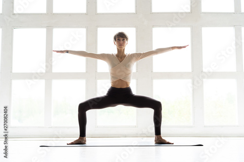 Young attractive yogi woman practicing yoga concept, sitting in Malasana exercise, Garland pose, working out, wearing sportswear, full length.