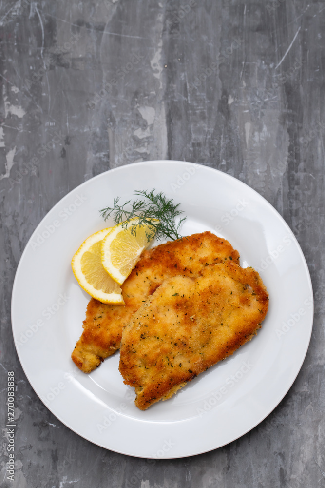 fried chicken with lemon on white plate on ceramic background fried chicken with lemon on white plate on ceramic background