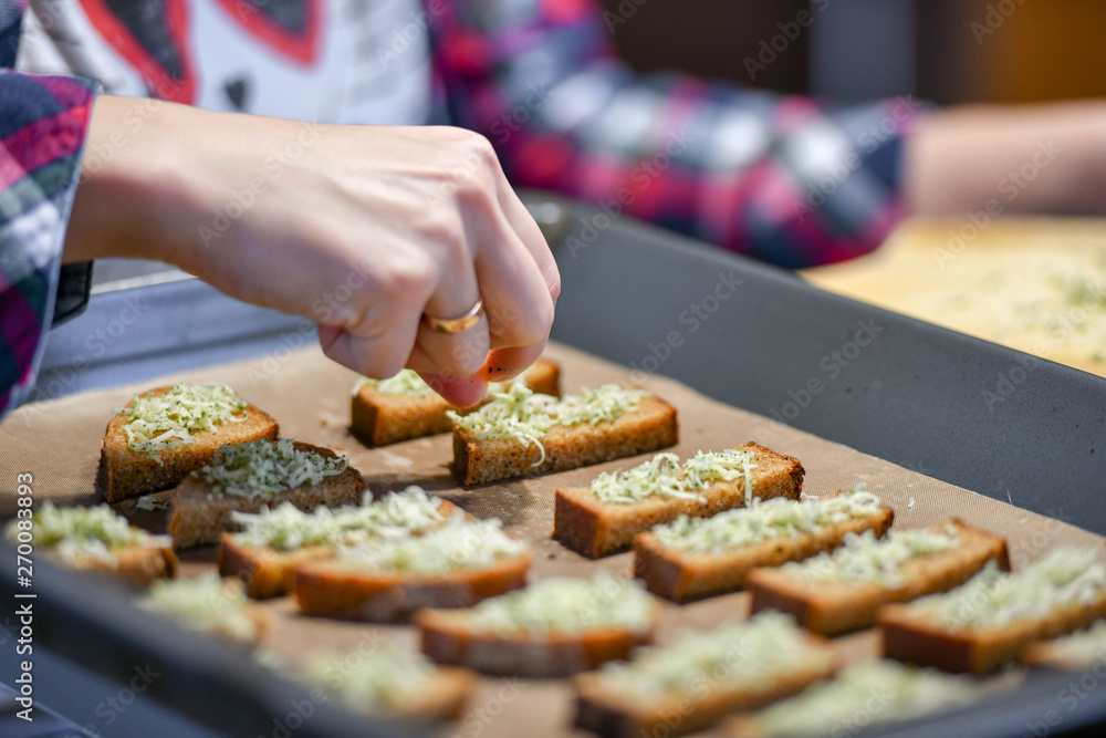 Black bread with cheese and seasonings, the girl sprinkles sliced bread.