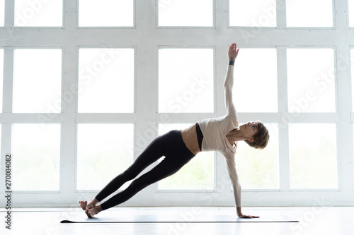 Young attractive Woman practicing home yoga, working out, wearing sportswear. Healthy life, keep fit concepts.