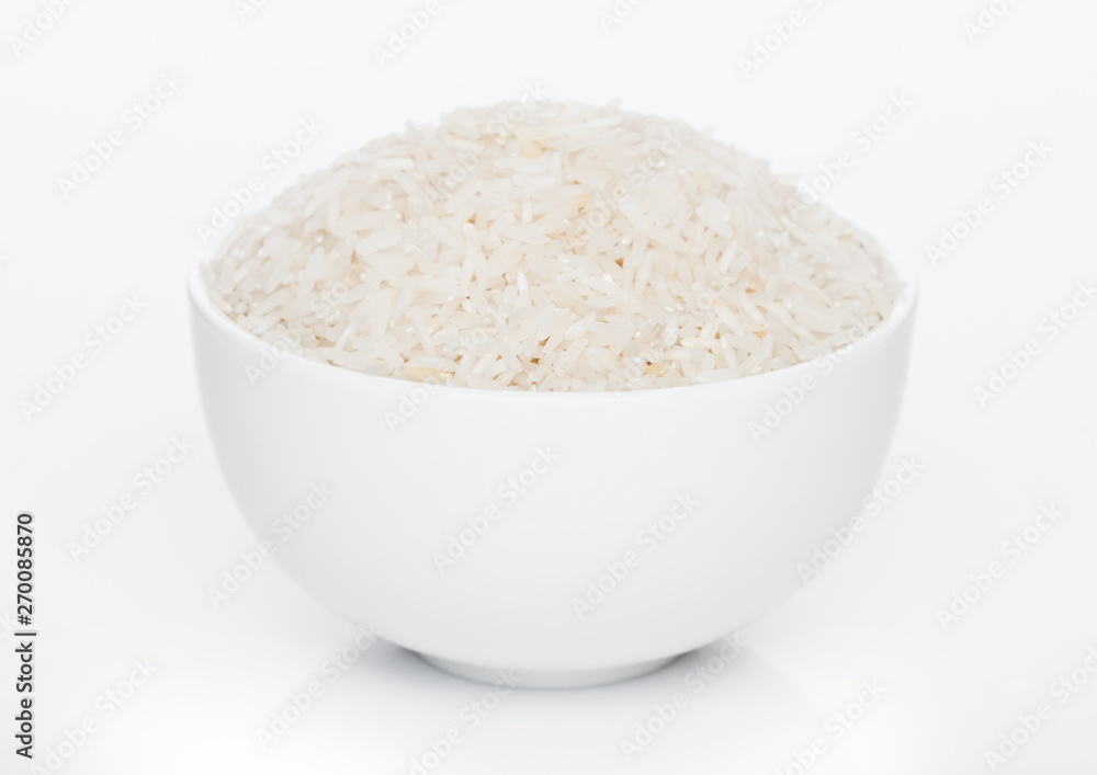 White bowl of raw organic basmati rice on white background. Healthy food. White bowl of raw organic basmati rice on white background. Healthy food.