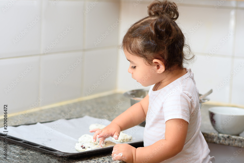 Little kid girl making pancakes on marble table. Happy family funny child are preparing the dough, bake cookies in the white kitchen. Little kid girl making pancakes on marble table. Happy family funny child are preparing the dough, bake cookies in the white kitchen.