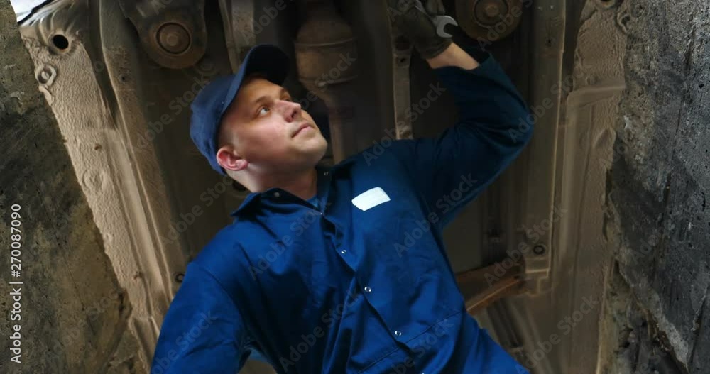 A cheerful car repairman on the street repairs the engine and lower part of the car, shows different emotions, dances with a big wrench. Concept of: Service, Joy, Slow motion, Mood, Happy, Repair. A cheerful car repairman on the street repairs the engine and lower part of the car, shows different emotions, dances with a big wrench. Concept of: Service, Joy, Slow motion, Mood, Happy, Repair.
