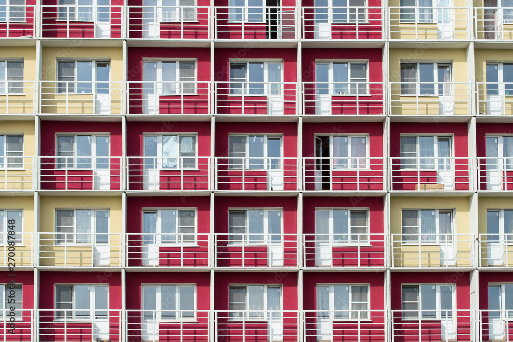 An apartment building red and yellow wall texture with balcony. Architecture background of building walls.