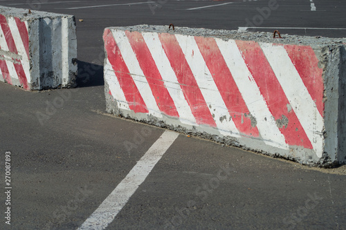 Rows of red and white concrete barriers used in traffic control and safety. Large slab of concrete used as a barrier at a construction site