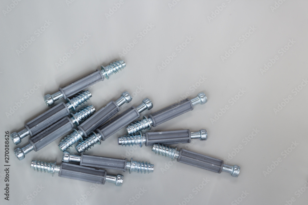 Couple of bolts with plastic dowels laying on flat metallic surface, copy space, top view Couple of bolts with plastic dowels laying on flat metallic surface, copy space, top view