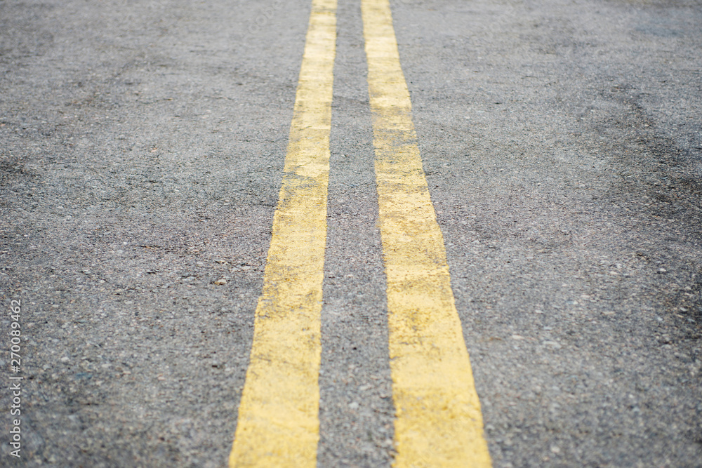 Fototapeta premium Yellow double solid line. Road markings on asphalt on the street. Highway surface with double yellow lines