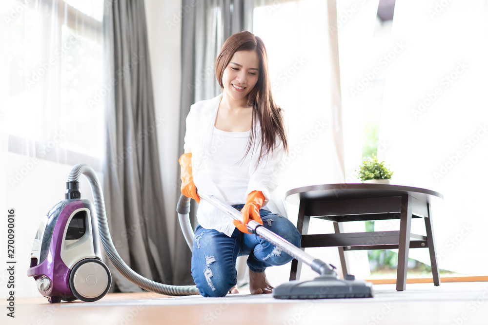 Happy Asian woman cleaning carpet with vacuum cleaner in living room. Housework, cleanig,chores concept