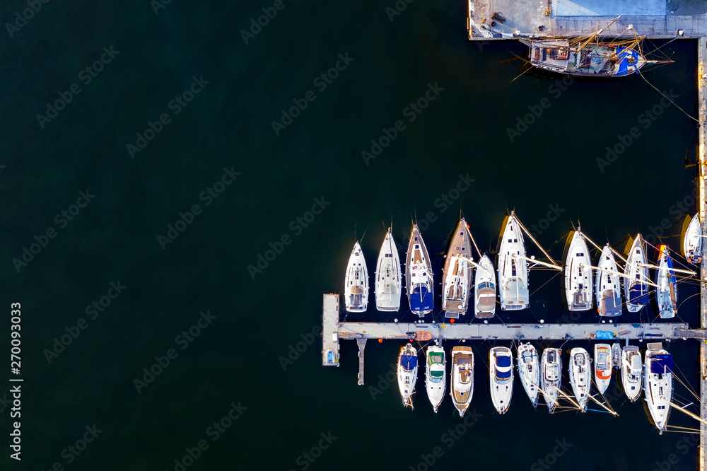 Aerial View by Drone of yachts and small motor boats. White boats in sea water. Yacht and sailboat are moored at the quay. Parking Aerial View by Drone of yachts and small motor boats. White boats in sea water. Yacht and sailboat are moored at the quay. Parking