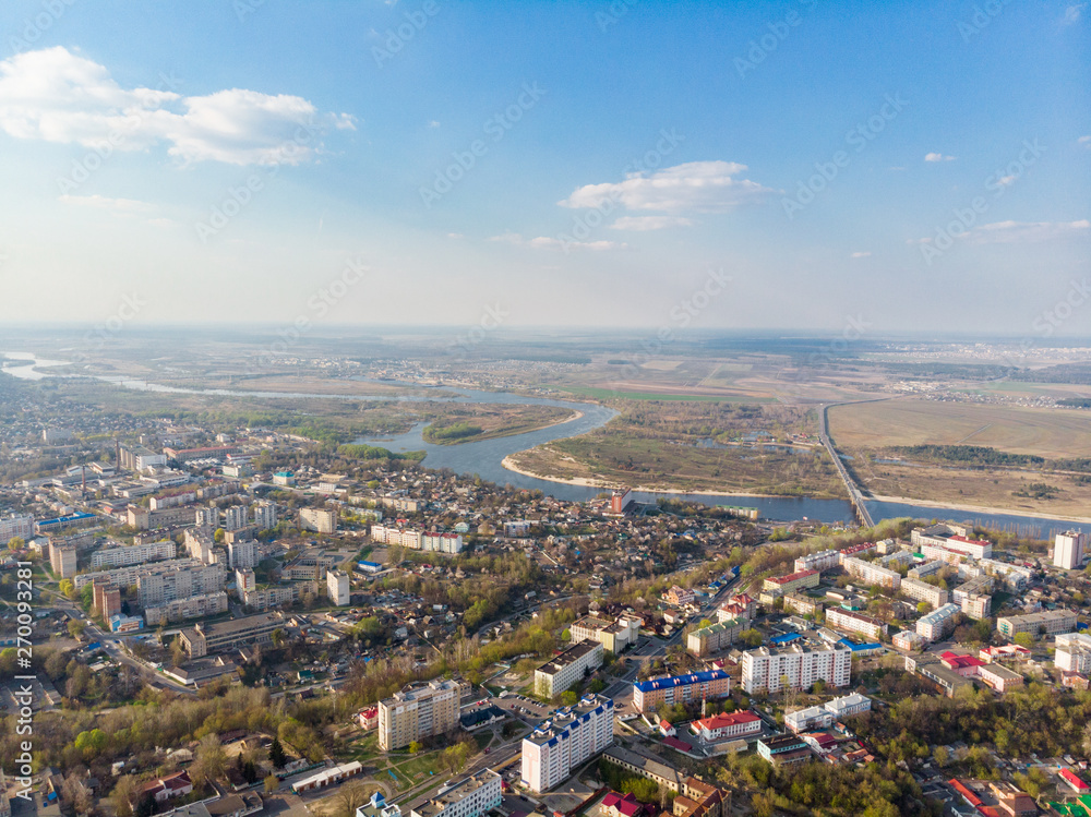 Panorama of a small town, river, forest, fields, road, bridge and sky. The photo was taken by a quadcopter, drone. Summer and spring. Skyview. Top view. Travel and tourism. Created by DGJ drone.
