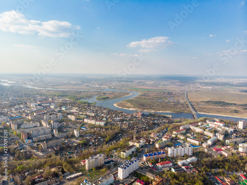 Panorama of a small town, river, forest, fields, road, bridge and sky. The photo was taken by a quadcopter, drone. Summer and spring. Skyview. Top view. Travel and tourism. Created by DGJ drone.