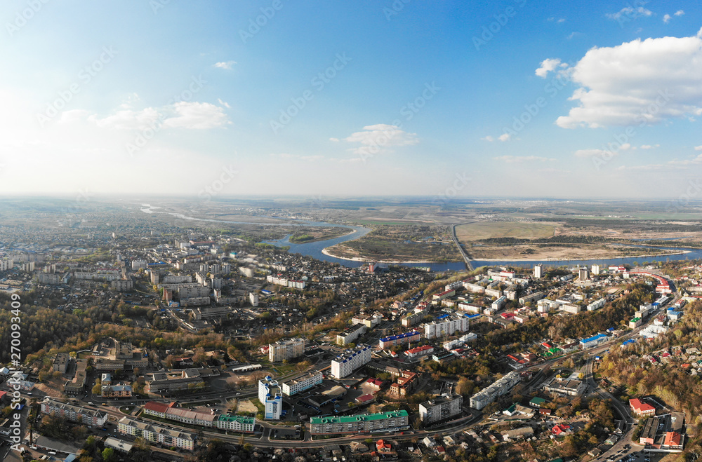 Panorama of a small town, river, forest, fields, road, bridge and sky. The photo was taken by a quadcopter, drone. Summer and spring. Skyview. Top view. Travel and tourism. Created by DGJ drone. Panorama of a small town, river, forest, fields, road, bridge and sky. The photo was taken by a quadcopter, drone. Summer and spring. Skyview. Top view. Travel and tourism. Created by DGJ drone.