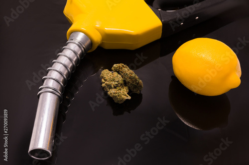 Cannabis flower with diesel pump handle and lemon on black background