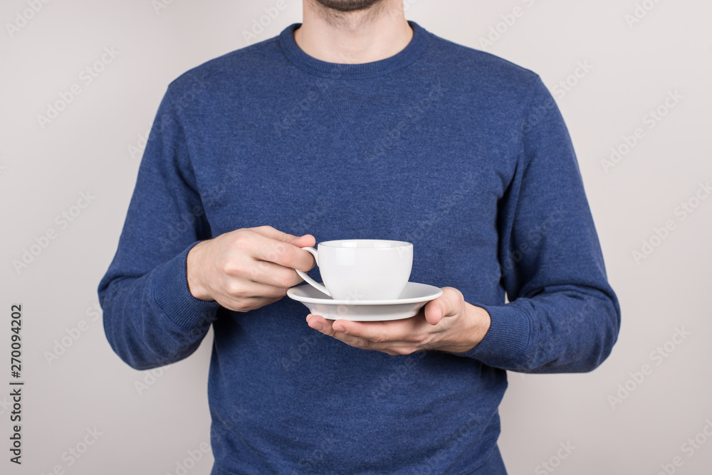 Close-up cropped view photo portrait of confident happy cool guy holding small cup in hands isolated grey background Close-up cropped view photo portrait of confident happy cool guy holding small cup in hands isolated grey background