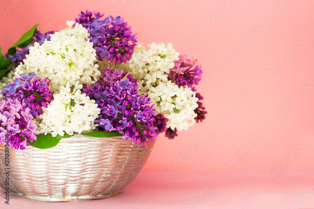 Lilac flowers bunch in a basket on blurred coral pink backgrond. Beautful fragrant Lilac Flowers bouquet with Copy space