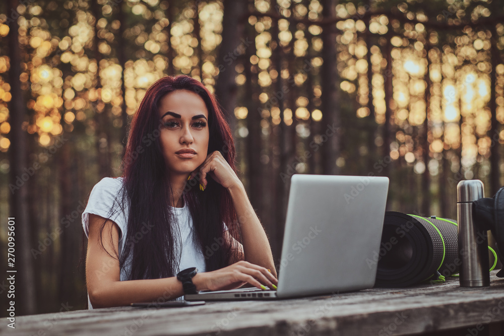 Beautiful young woman is working on the laptop in the middle of the forest. Beautiful young woman is working on the laptop in the middle of the forest.