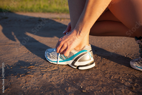 Young woman runner tying shoelaces. Healthy lifestyle and sport concept for exercising and fitness.